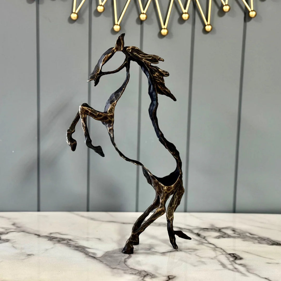 Bronze horse sculpture on a marble surface with a decorative metal frame in the background.