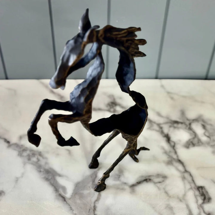 Bronze horse sculpture on a marble surface with a gray tiled wall background