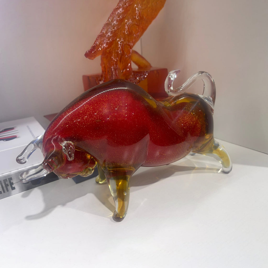 Glass sculpture of a red and orange creature on a white surface