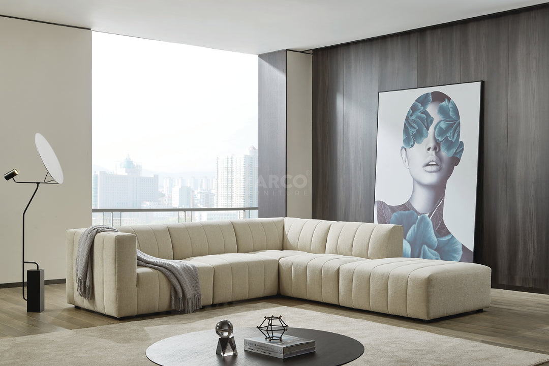 Modern living room with a beige sectional sofa, round coffee table, and artwork on the wall.