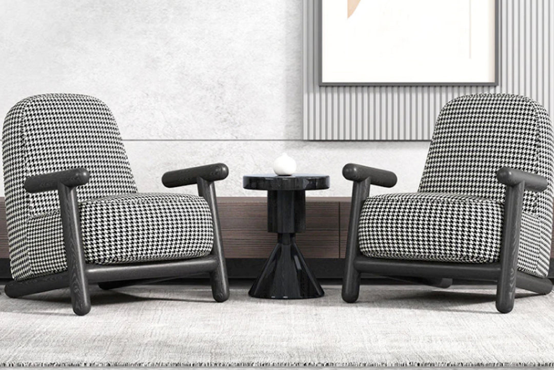 Two houndstooth-patterned chairs with a small round table in a room setting.
