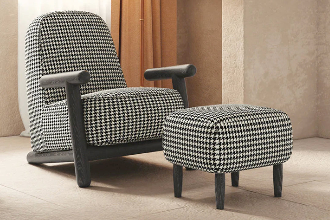 Black and white houndstooth-patterned armchair and ottoman in a room with beige walls and floor.