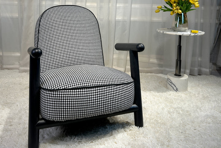 Black and white checkered armchair in a room with a small table and flowers.