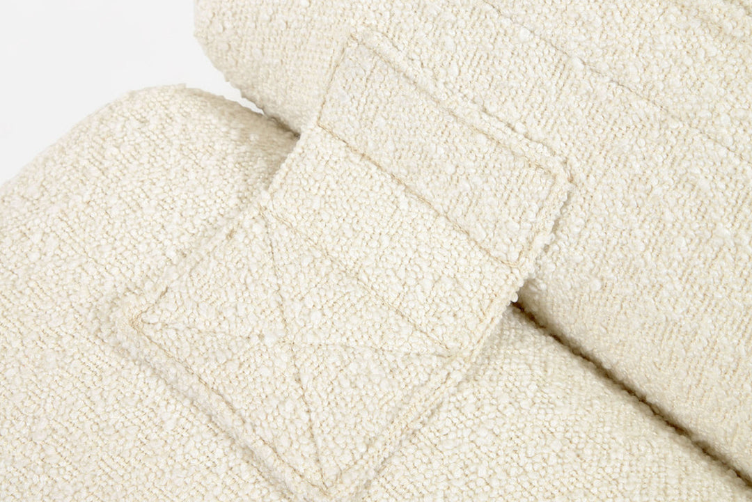 Close-up of a textured beige fabric with a subtle pattern on a light gray background