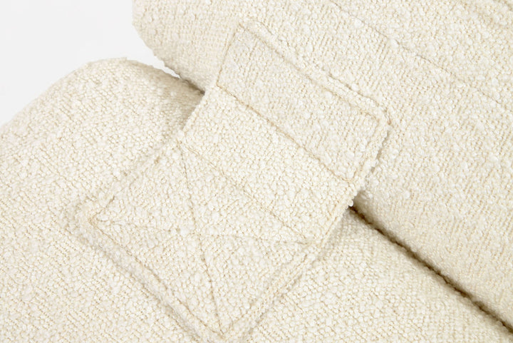 Close-up of a textured beige fabric with a subtle pattern on a light gray background