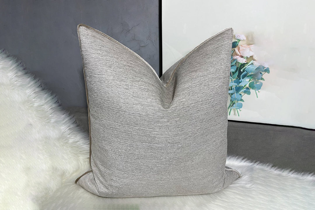 Gray textured pillow on a white surface with a blurred background
