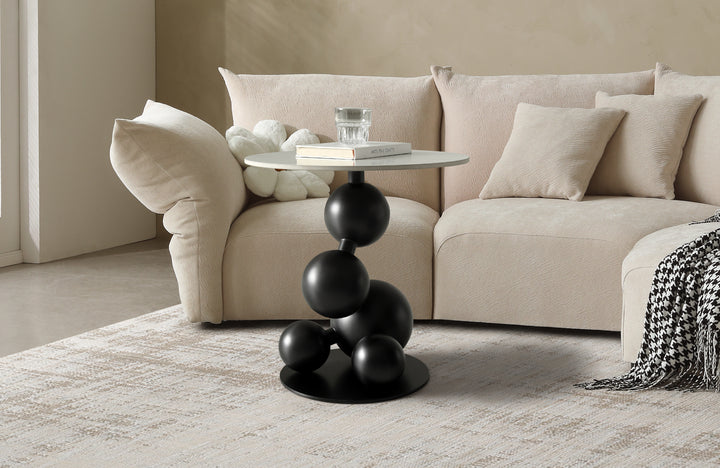Modern living room with a beige sofa and a black side table with spherical design.