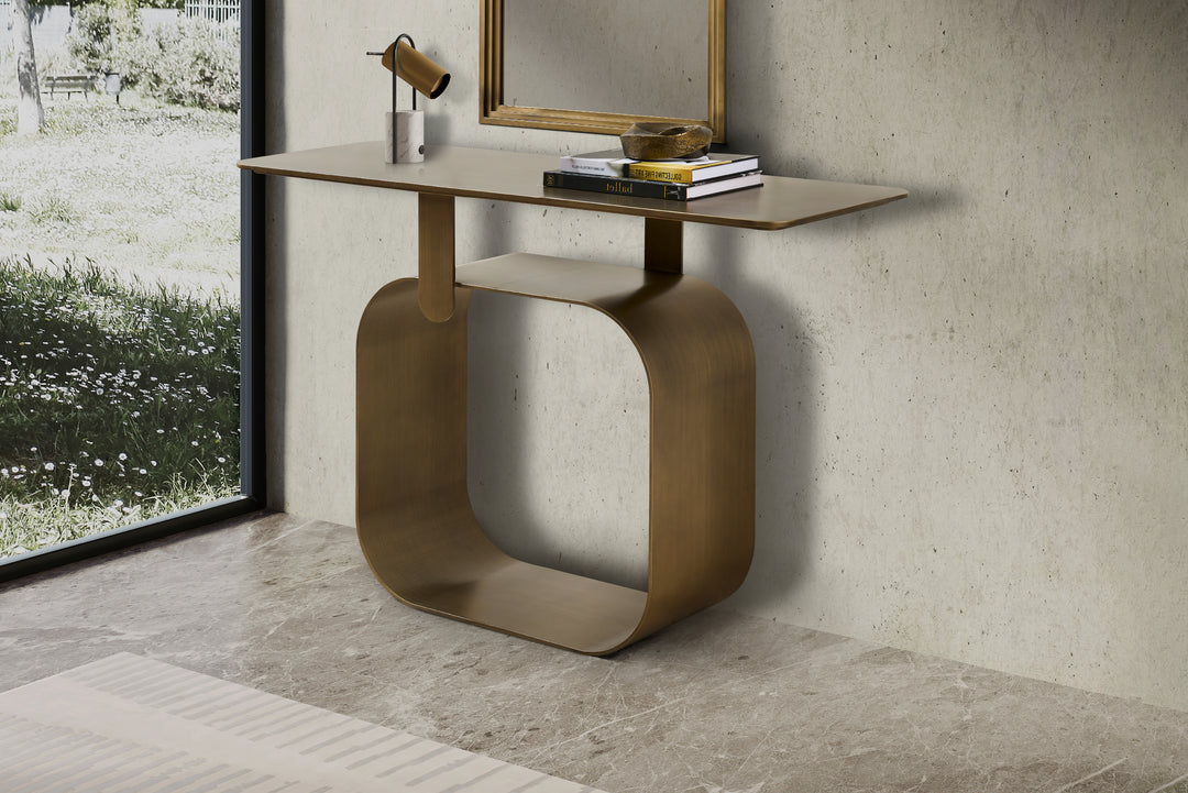 Modern console table with gold base and wooden top in a room with concrete wall and window.