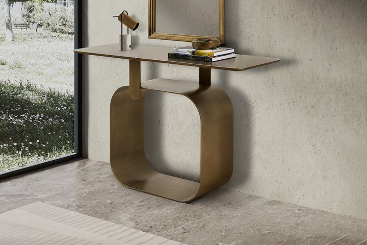 Modern console table with gold base and wooden top in a room with concrete wall and window.