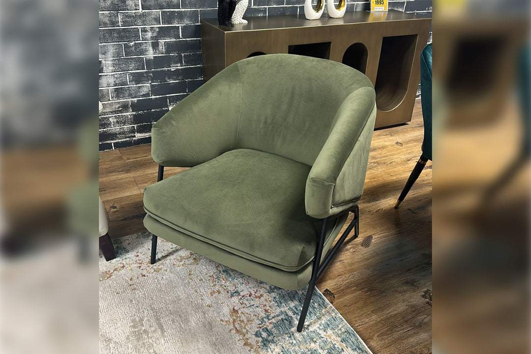 Green armchair in a room with a brick wall and wooden floor.