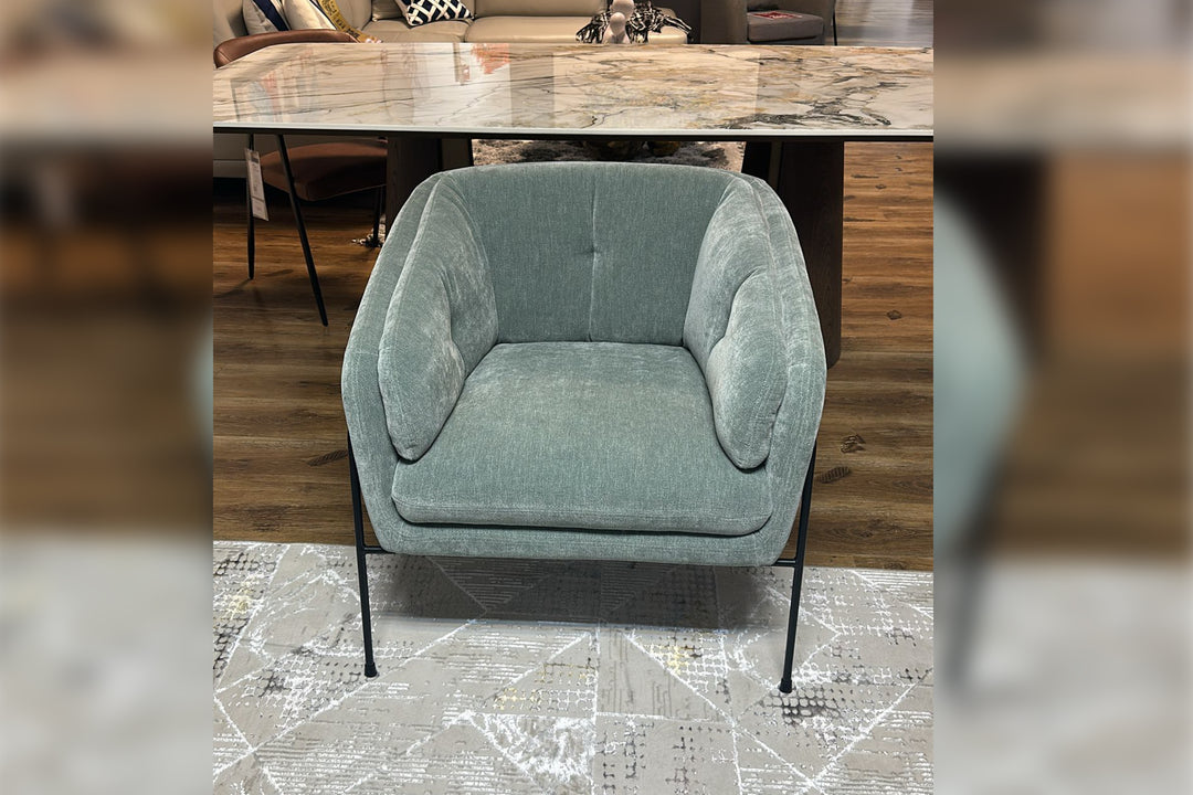 Gray armchair in a room with wooden flooring and a table.