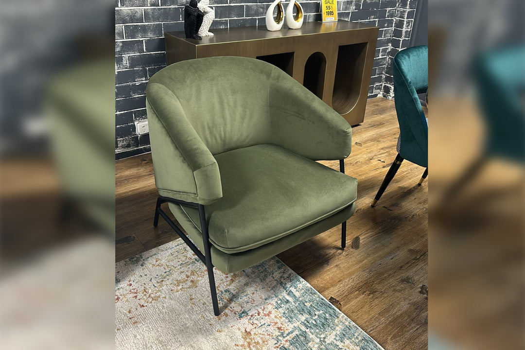 Green armchair in a room with a brick wall and wooden floor.