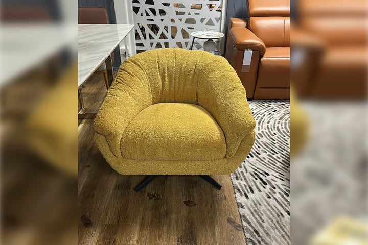 Yellow armchair in a showroom setting with brown leather sofa and wooden floor.