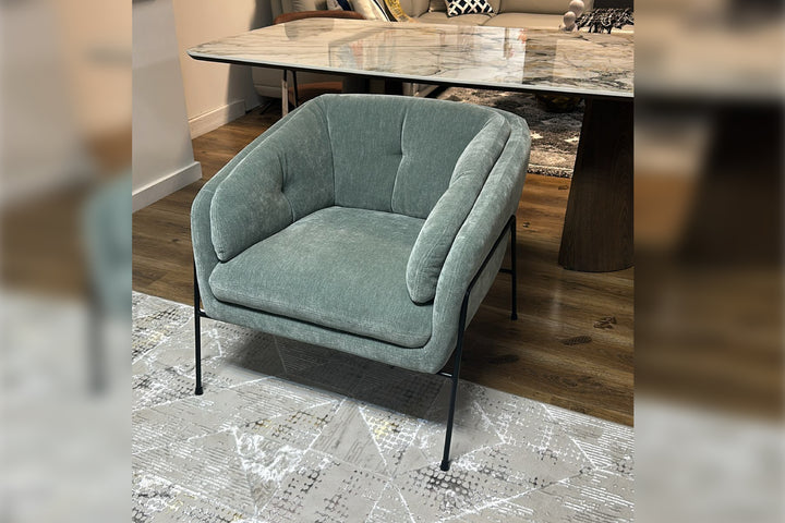 Blue armchair in a room with a marble table and wooden floor.