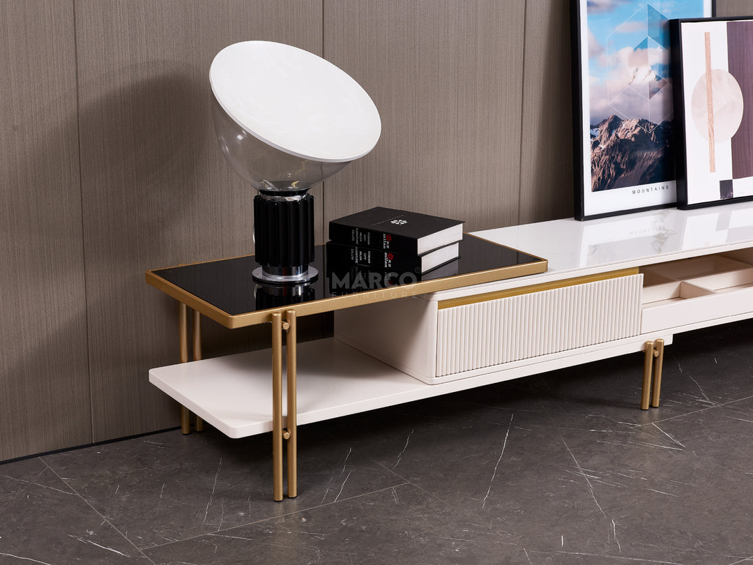 Modern TV stand with a lamp and books against a wooden wall.