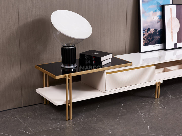 Modern TV stand with a lamp and books against a wooden wall.