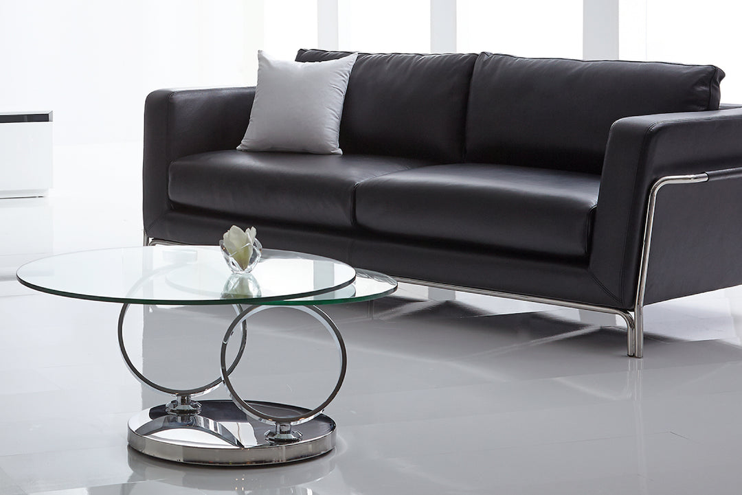 Black leather sofa in a modern living room with a glass coffee table.
