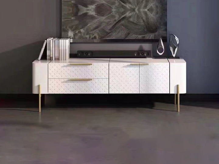 A glossy white Bravia TV console with gold stainless steel legs, featuring two large drawers and two cabinets, with gold-toned accents.