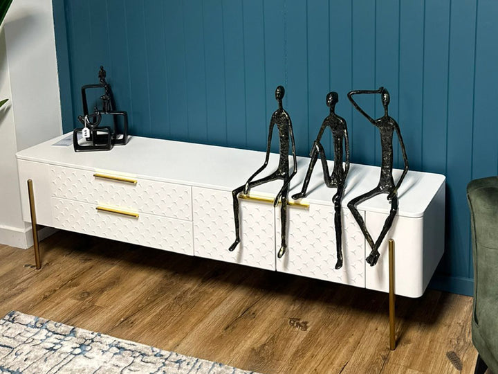 White entertainment console with black metal figurines against a blue wall.