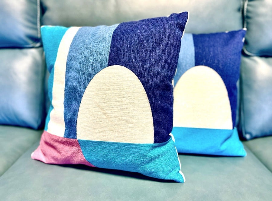 Two square Brayden cushions with geometric patterns on a sofa.