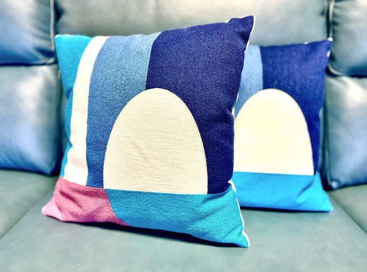 Two square Brayden cushions with geometric patterns on a sofa.
