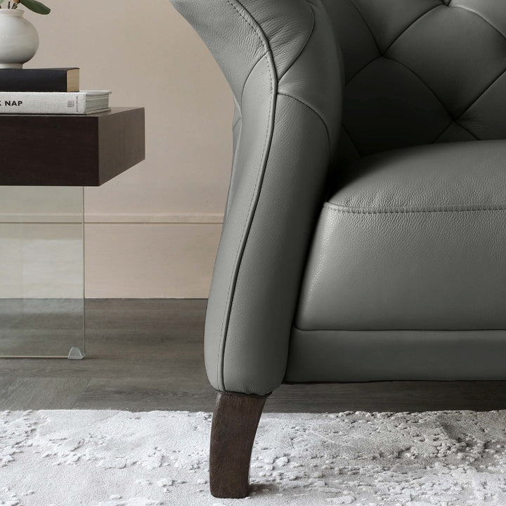 Gray leather armchair with wooden legs in a room setting.