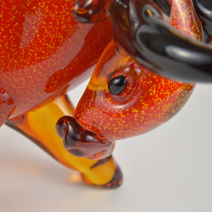 Close-up of a glass insect figurine with red and orange speckled body on a white background