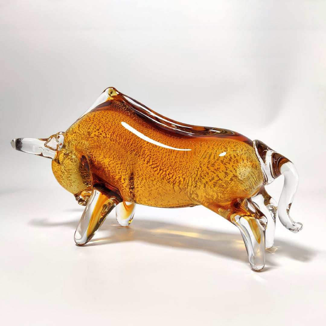 Glass bull sculpture with amber-colored body on a white background