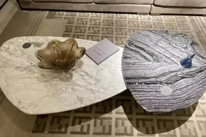 Two marble coffee tables with decorative items in a living room.