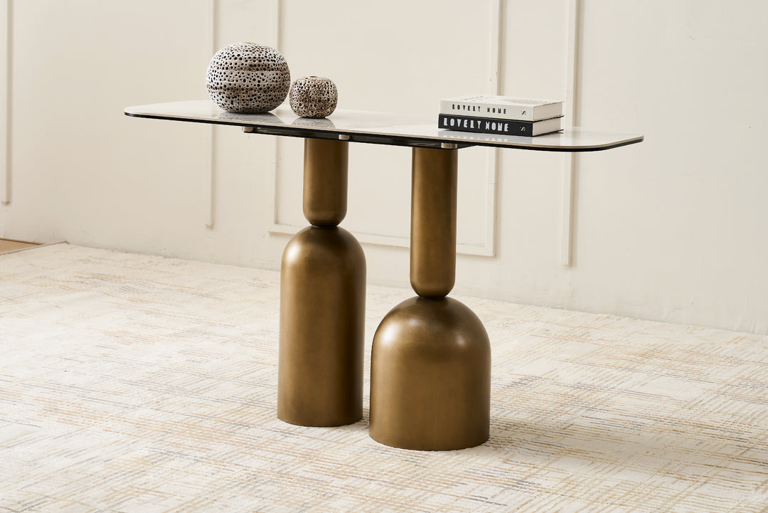 Modern side table with bronze cylindrical legs and a glass top on a light wooden floor.