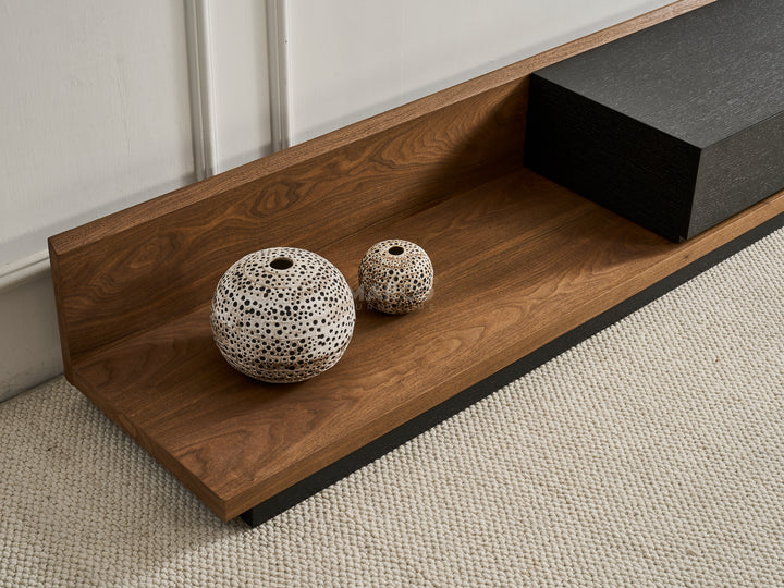 Two decorative vases on a wooden shelf next to a black cabinet.