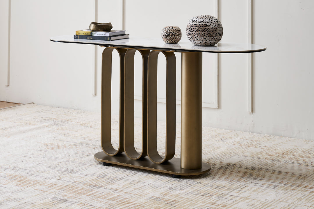 Modern console table with glass top and bronze metal base in a room setting.