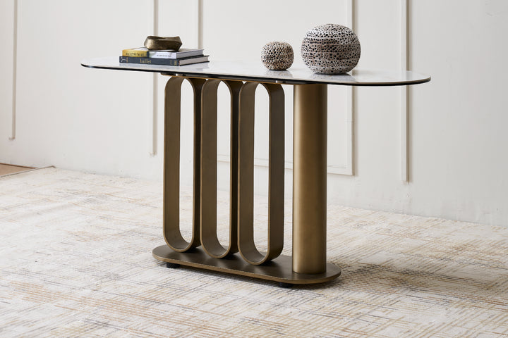 Modern console table with glass top and bronze metal base in a room setting.