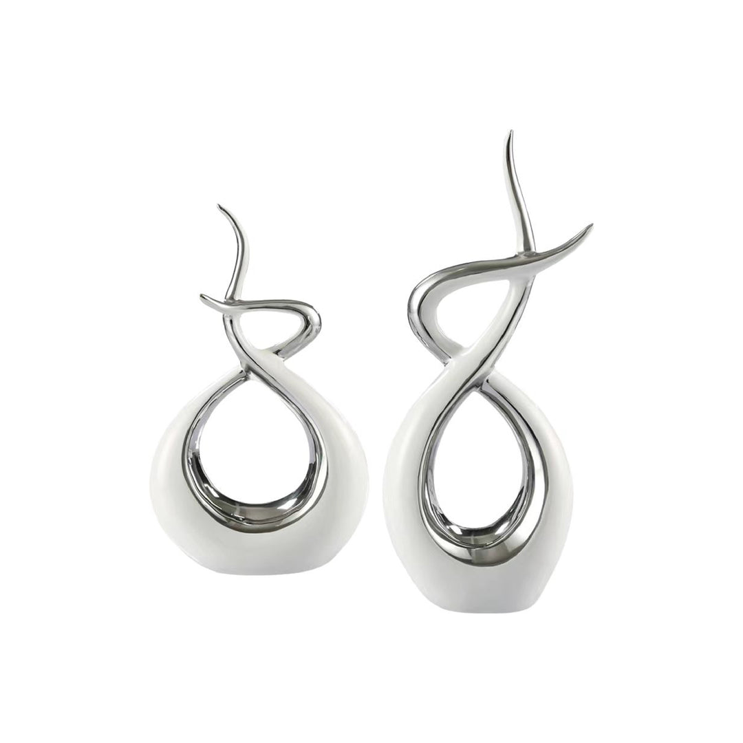 A pair of ceramic flame sculptures with white and silver colors, featuring abstract flame-like lines.