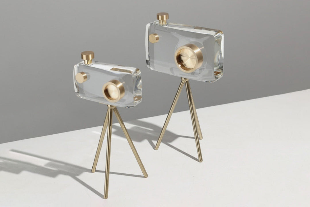 Two clear and gold decorative items on stands against a gray background