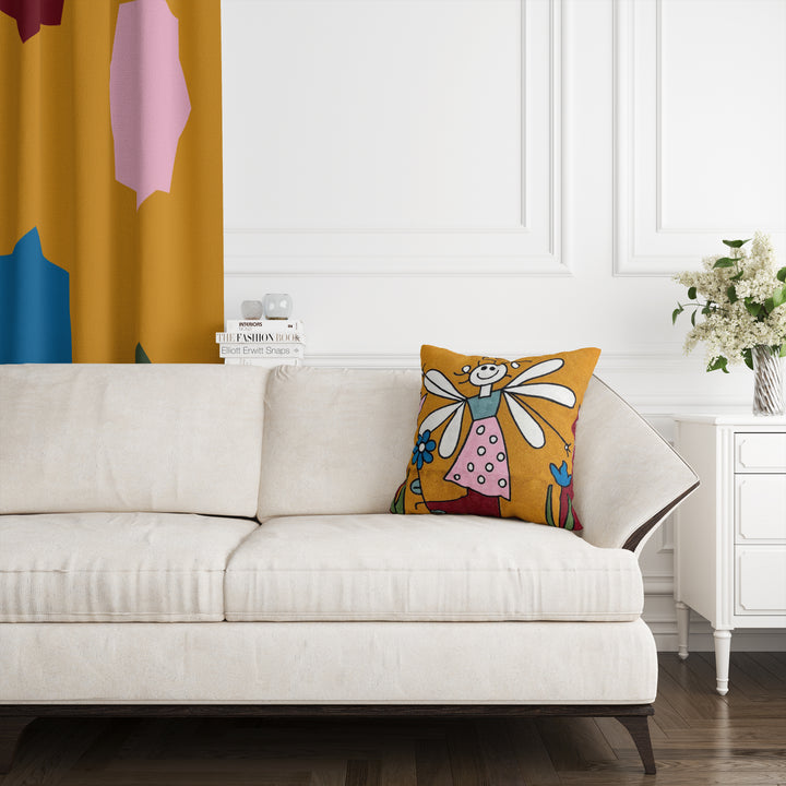 A cushion cover featuring a colorful design with a character resembling Tinker Bell on a sofa in a room with a white wall and a decorative yellow curtain.