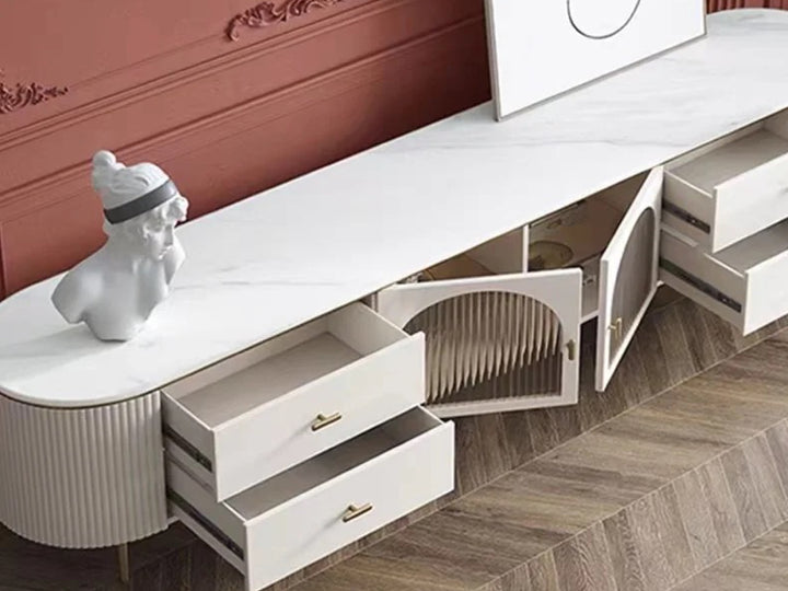 Modern white entertainment console with drawers and open shelf against a red wall.