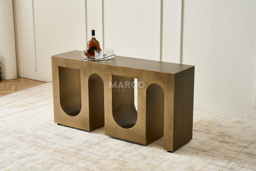 Bronze console table with a bottle and glass on a textured floor, branded 'Margo Furniture'.