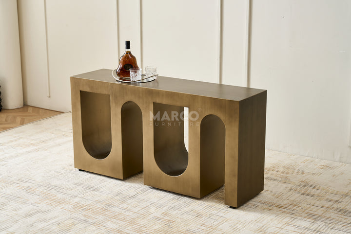 Bronze console table with a bottle and glass on a textured floor, branded 'Margo Furniture'.