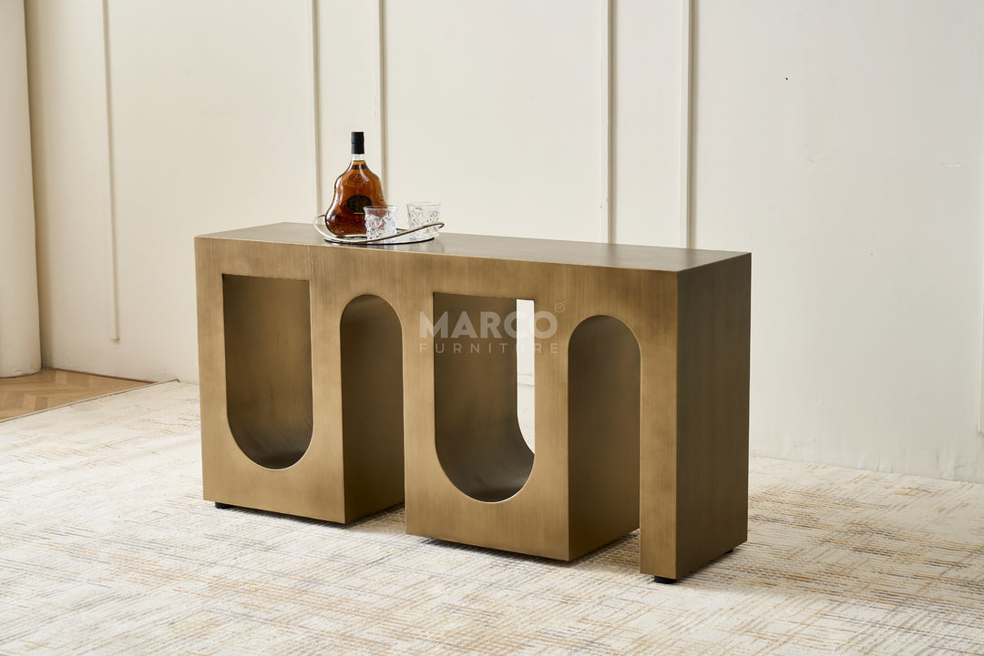 Bronze console table with a bottle and glass on a light-colored floor.