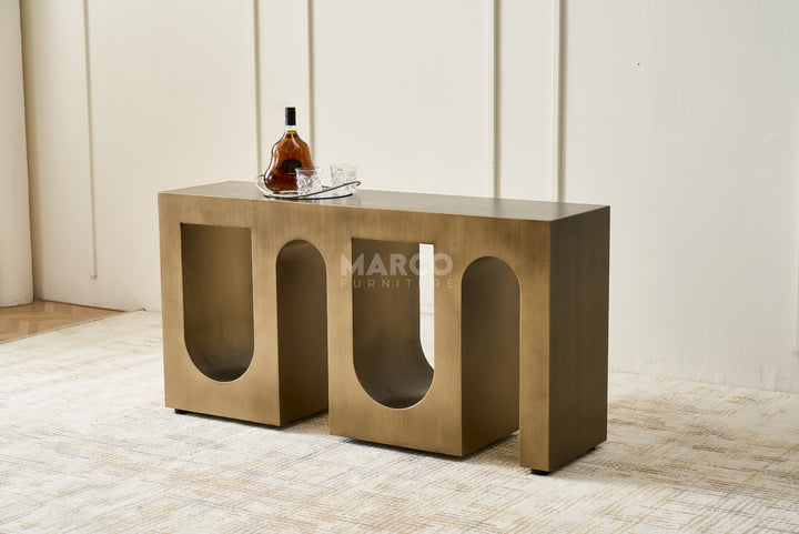 Bronze console table with a bottle and glass on a light-colored floor.