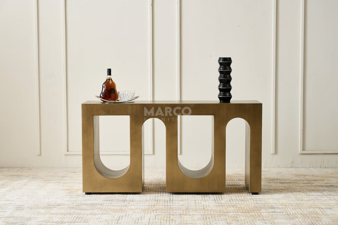 Bronze side table with decorative items against a white paneled wall.