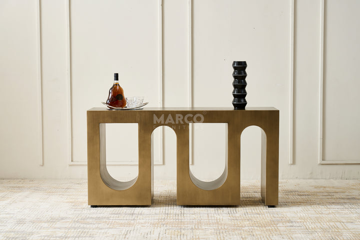 Bronze side table with decorative items against a white paneled wall.