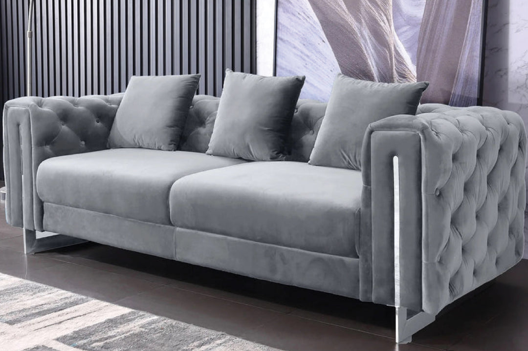 Gray tufted sofa with decorative pillows in a room setting.