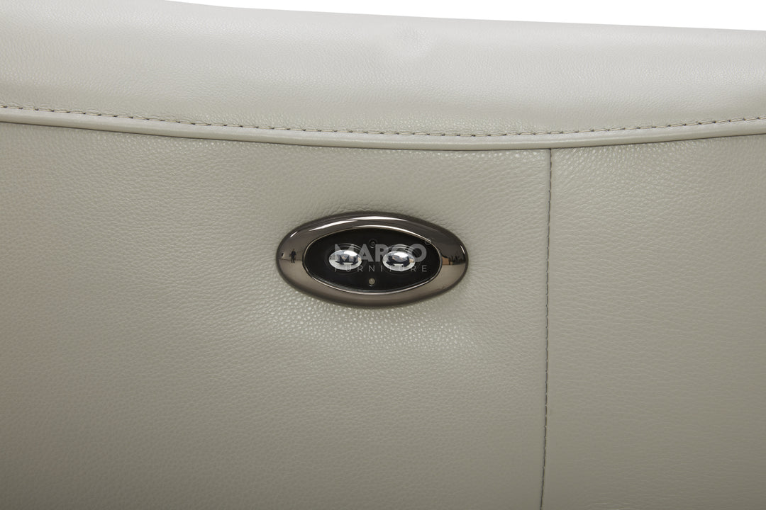 Close-up of a beige leather product with a silver logo on a white background