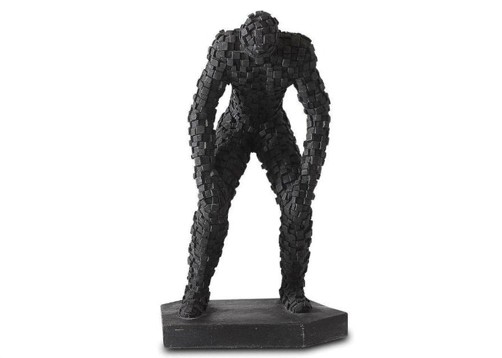 A black sandstone figurine of a standing man with arms crossed, featuring a mosaic texture.