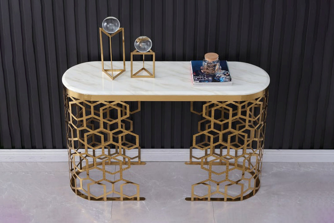 Decorative console table with marble top and gold geometric legs against a dark curtain background