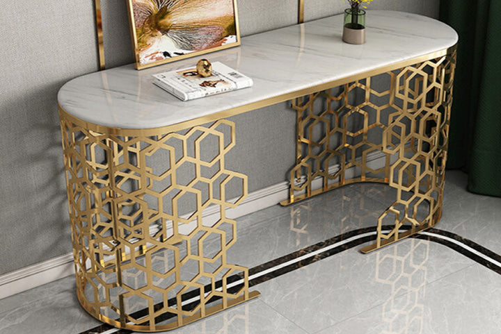 Decorative console table with marble top and gold geometric legs against a gray wall.