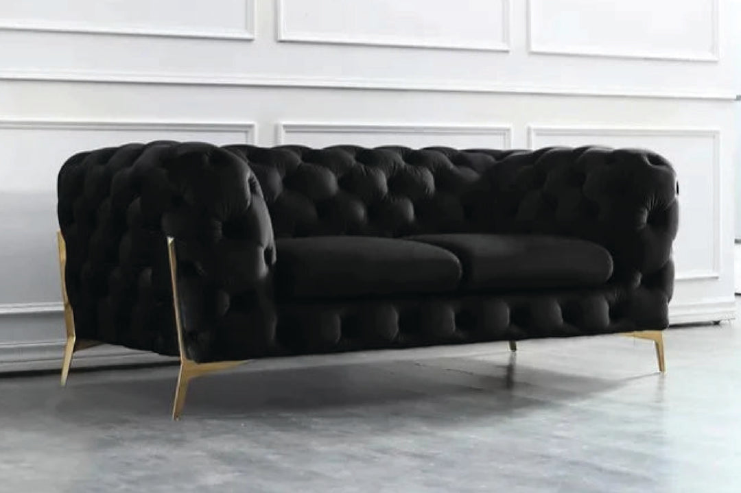 Black tufted sofa with gold legs in a minimalistic room.