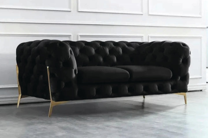 Black tufted sofa with gold legs in a minimalistic room.